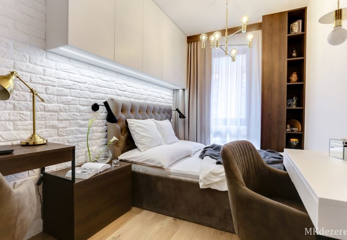 Aranżacja małej sypialni z szafami, biurkiem oraz toaletką.