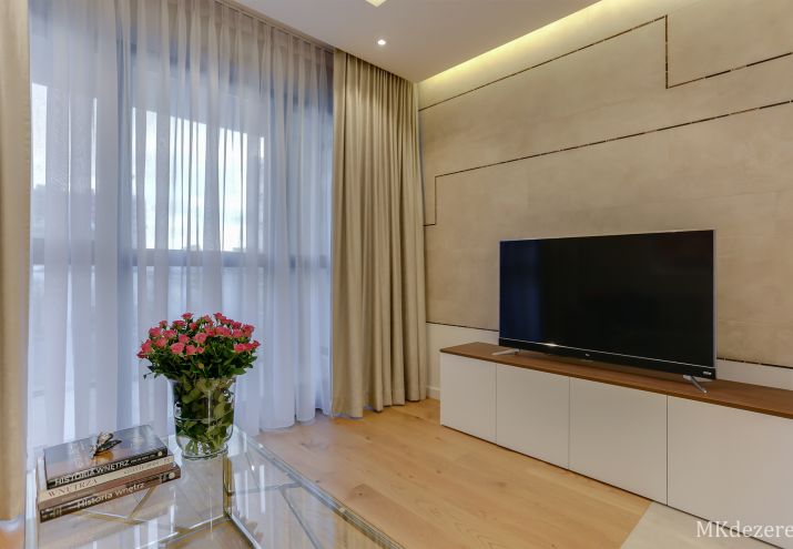 Elegancka zabudowa ściany telewizyjnej oświetlona dekoracyjnym światłem ukrytym w suficie podwieszanym.