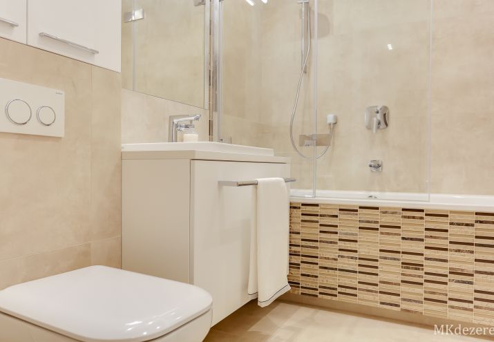 Nowoczesna, jasna łazienka z mozaiką na wannie.