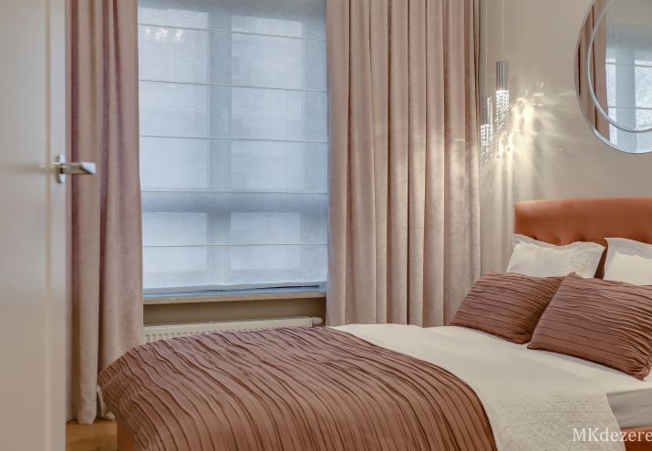 Aranżacja małej sypialni z wygodnym łóżkiem tapicerowanym i dużą białą szafą.