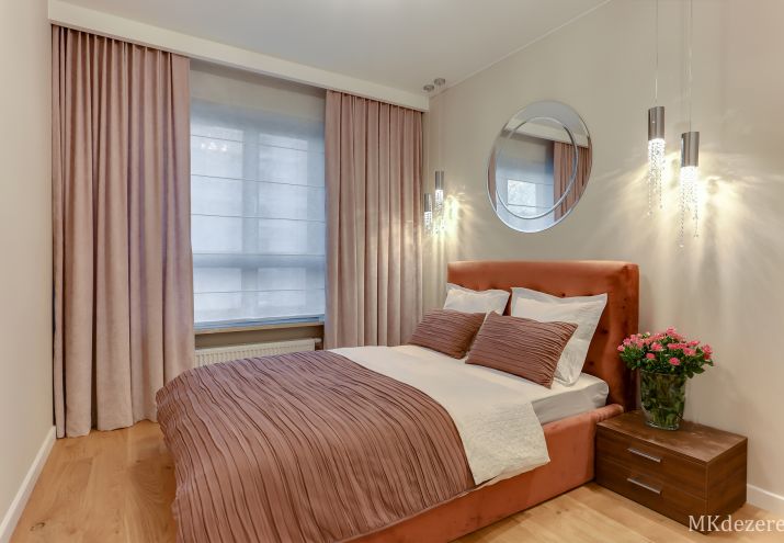 Aranżacja przytulnej sypialni, łóżko z tapicerowanym zagłówkiem, lampy z kryształkami, lustro w sypialni.