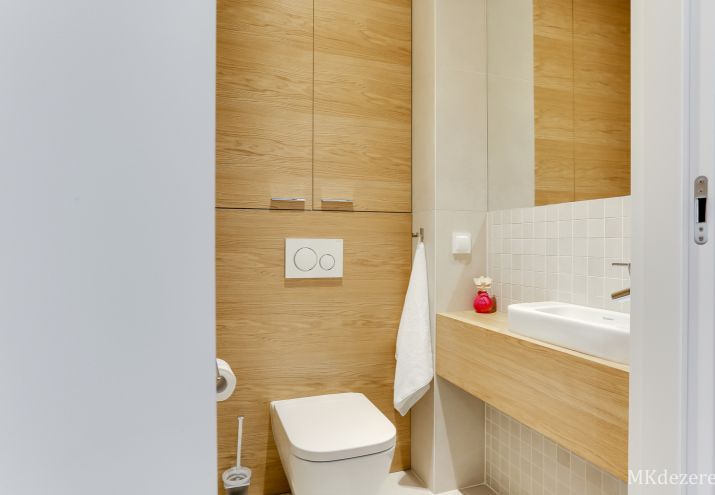 Łazienka z wc, mała umywalka stojąca na drewnianym blacie.