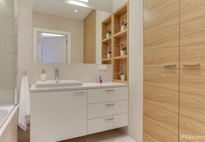 Aranżacja łazienki z dużą szafką oraz wbudowaną umywalką. Pralka zabudowana w szafie.