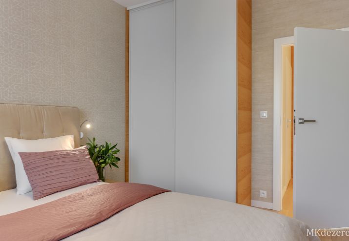 W sypialni znajduje się duża szafa z drzwiami przesuwnymi.