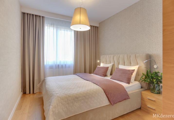 Łóżko tapicerowane w sypialni z pojemnikiem w beżach, ściany pokryte tapetą.